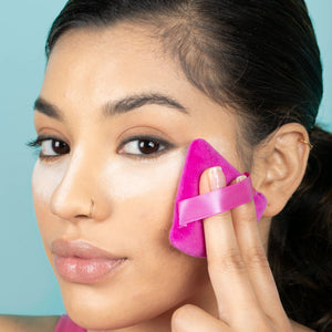 Magenta powder puff with finger band pressed to cheek