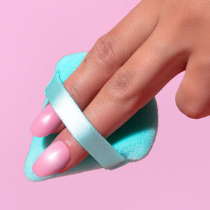 Light blue powder puff with finger band, held by hand