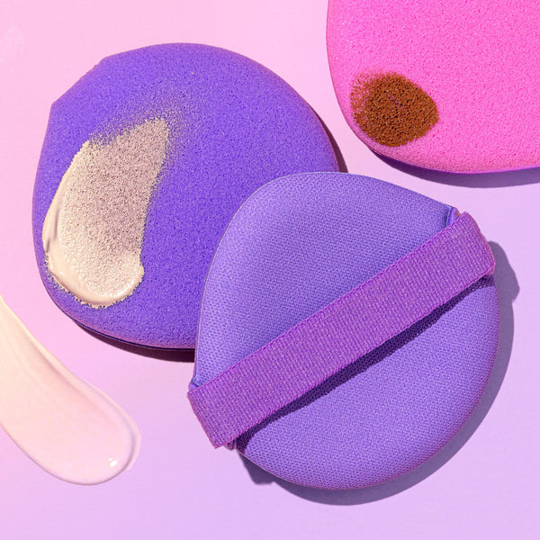 Set of three round liquid makeup puffs in lavender, purple, and pink with bands