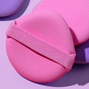 Pink liquid makeup puff with ribbed strap, rounded dome sponge for applying foundation