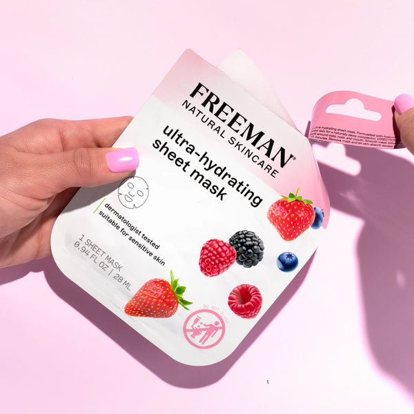 Hand holding Freeman ultra-hydrating sheet mask pouch, front label with berry icons