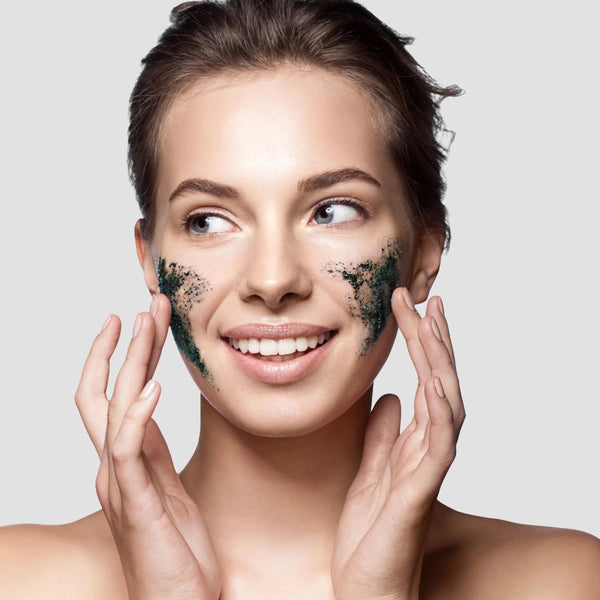 Woman with dark charcoal + black sugar gel mask covering cheeks and chin