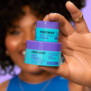 Hands holding two Freeman rich overnight leave-on cream jars, blue and purple