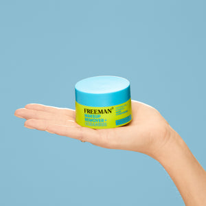 Freeman makeup remover cleansing balm jar held in open palm, blue lid.