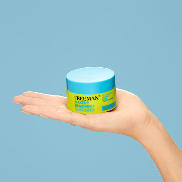 Freeman makeup remover cleansing balm jar held in open palm, blue lid.