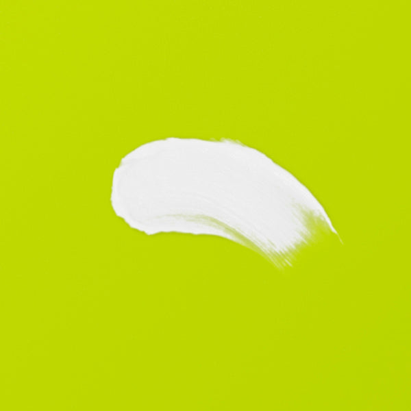 White cleansing balm smear on green surface, product texture detail.